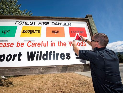 Fire personnel changing fire risk rating sign to extreme