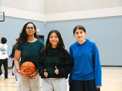 Three young girls playing basketball at Pinetree Community Centre.