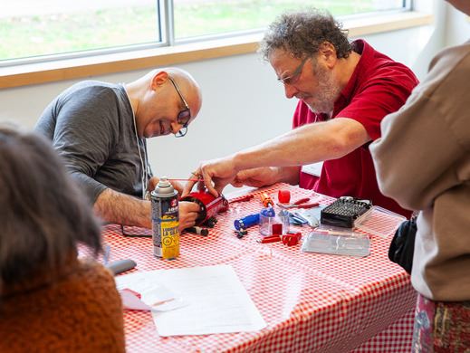 two men working at repairing a mechanical item