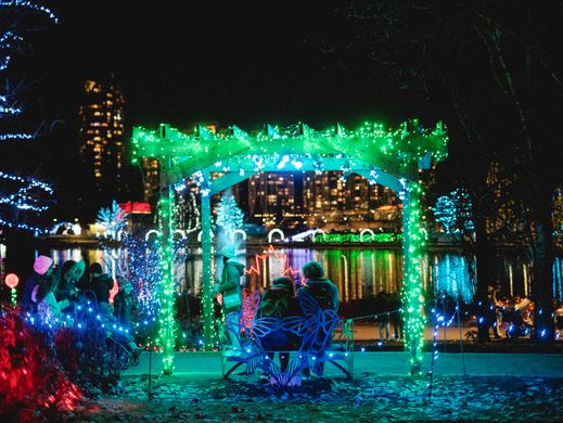 Couple sitting on a bench underneath a lit archway at Lights at Lafarge kick-off event at night.