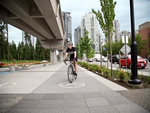 A man in black biking gear on a bike pedals along the bike path on Pinetree Way 