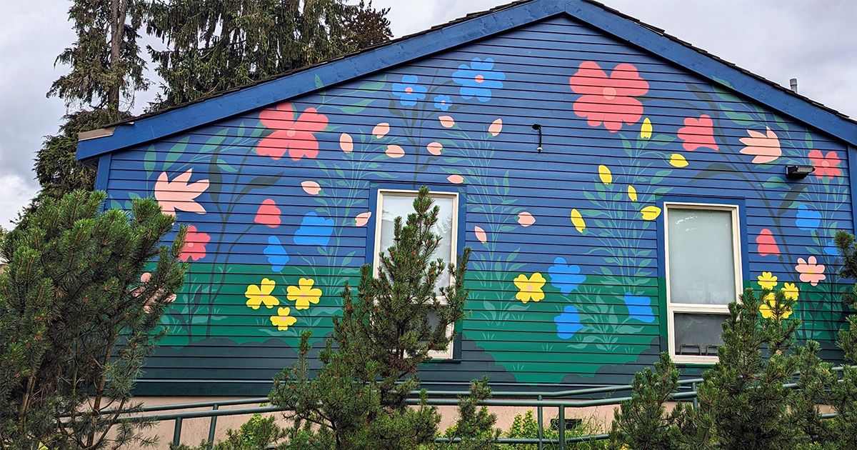 The first finished mural. A dark blue background with large colourful flowers. Opens in new window