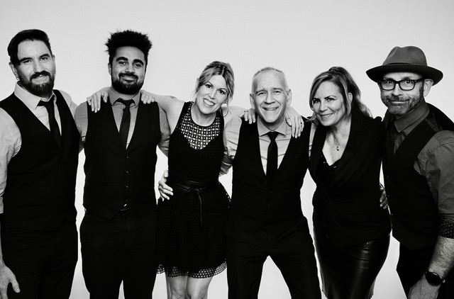 Four members of the band Dr. Strangelove posing in front of a white background.