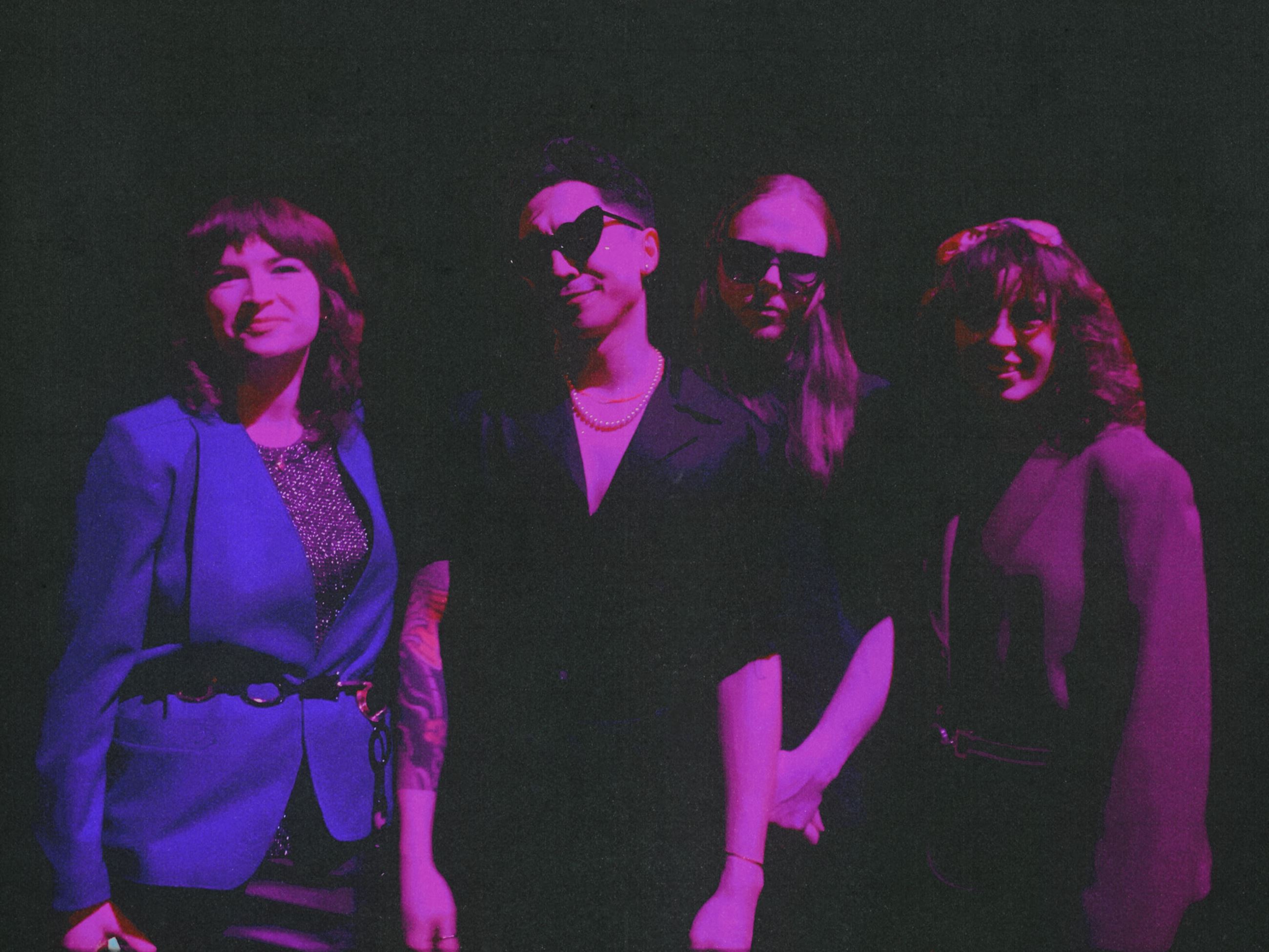 Four members of Frankie and the Juicebox band standing against blackdrop