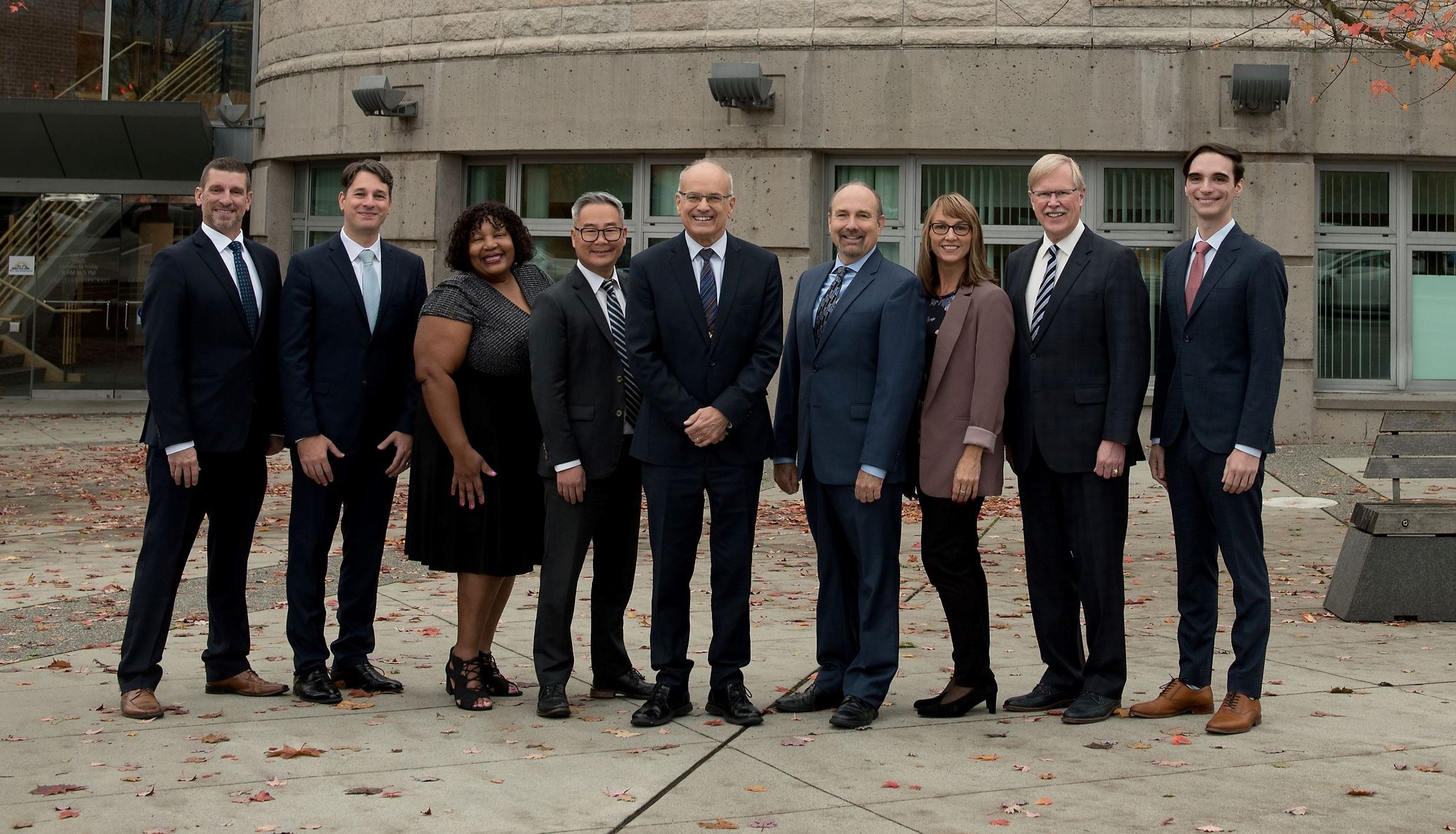 Group photo of Mayor and Councillors standing outside of City Hall, dressed sharply.